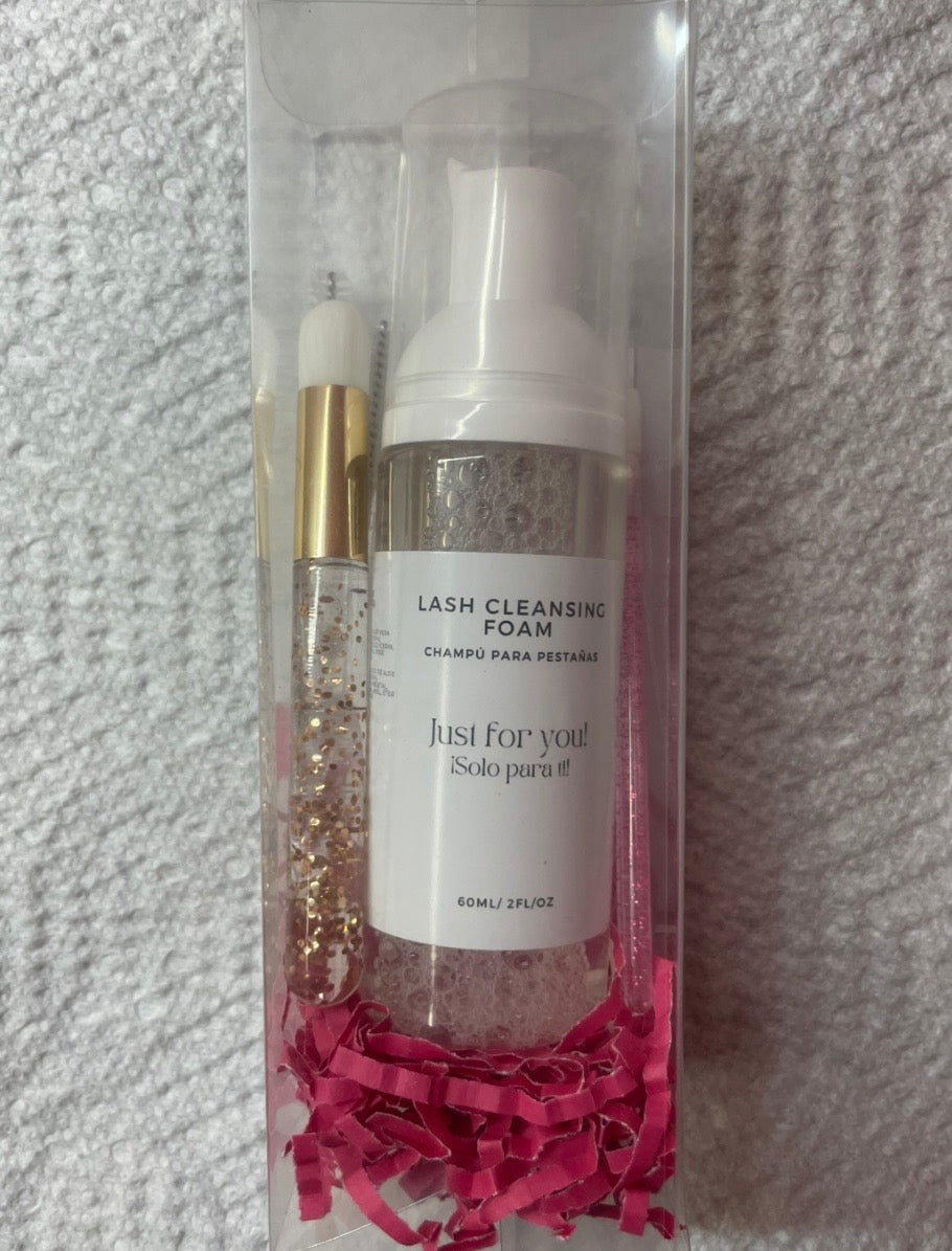 Lash cleansing foam in a clear packaging with pink tissue paper on a textured gray background